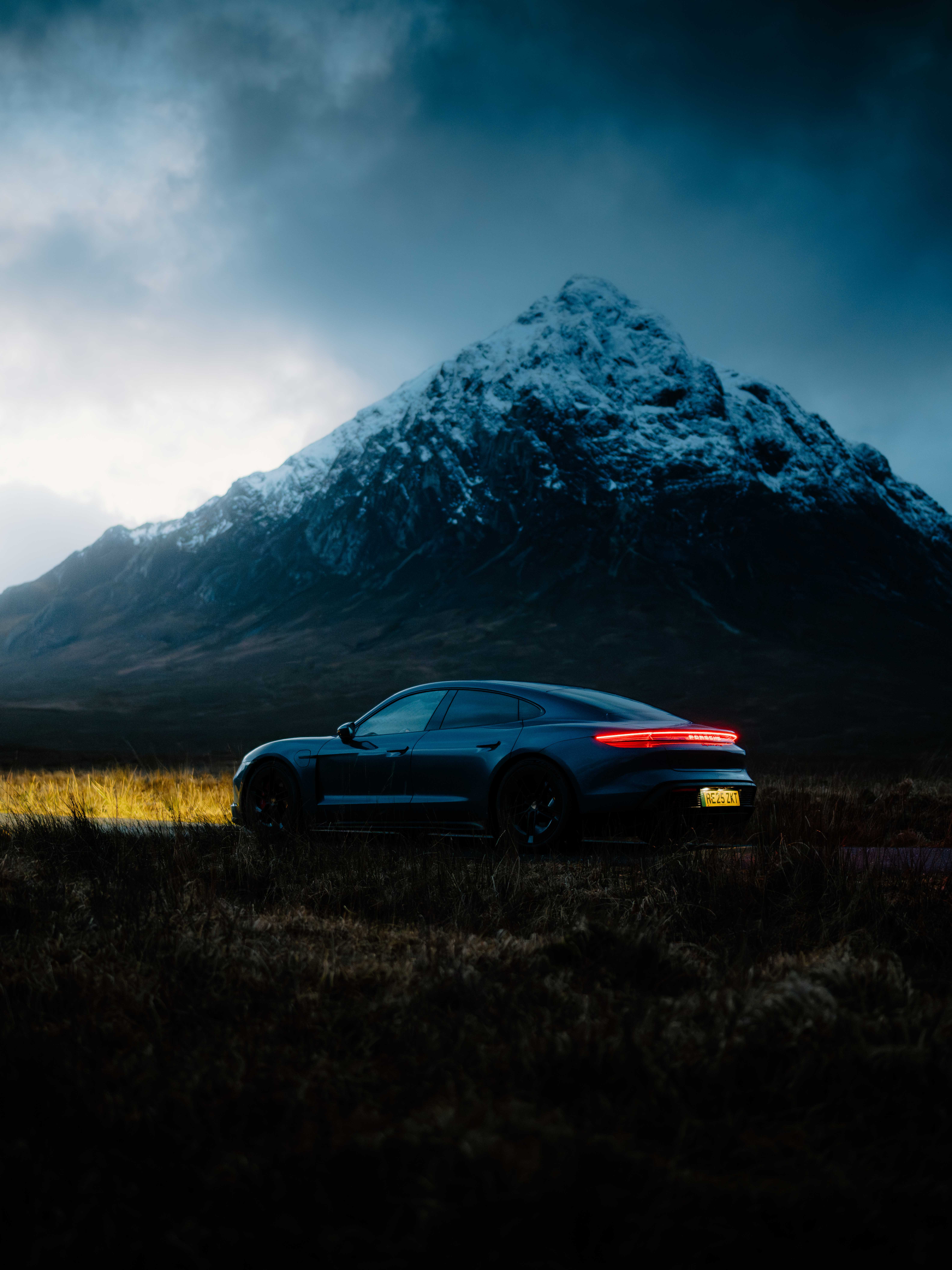 A black Porsche at sunset with a mountain in the background